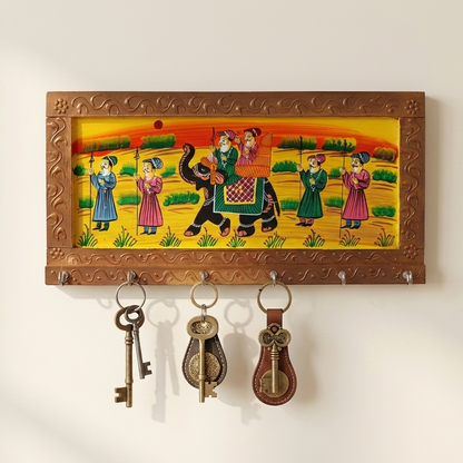 A golden-brown ethnic wooden key hanger mounted on a wall, holding keys  on its metal hooks, showcasing hand-painted Indian art.