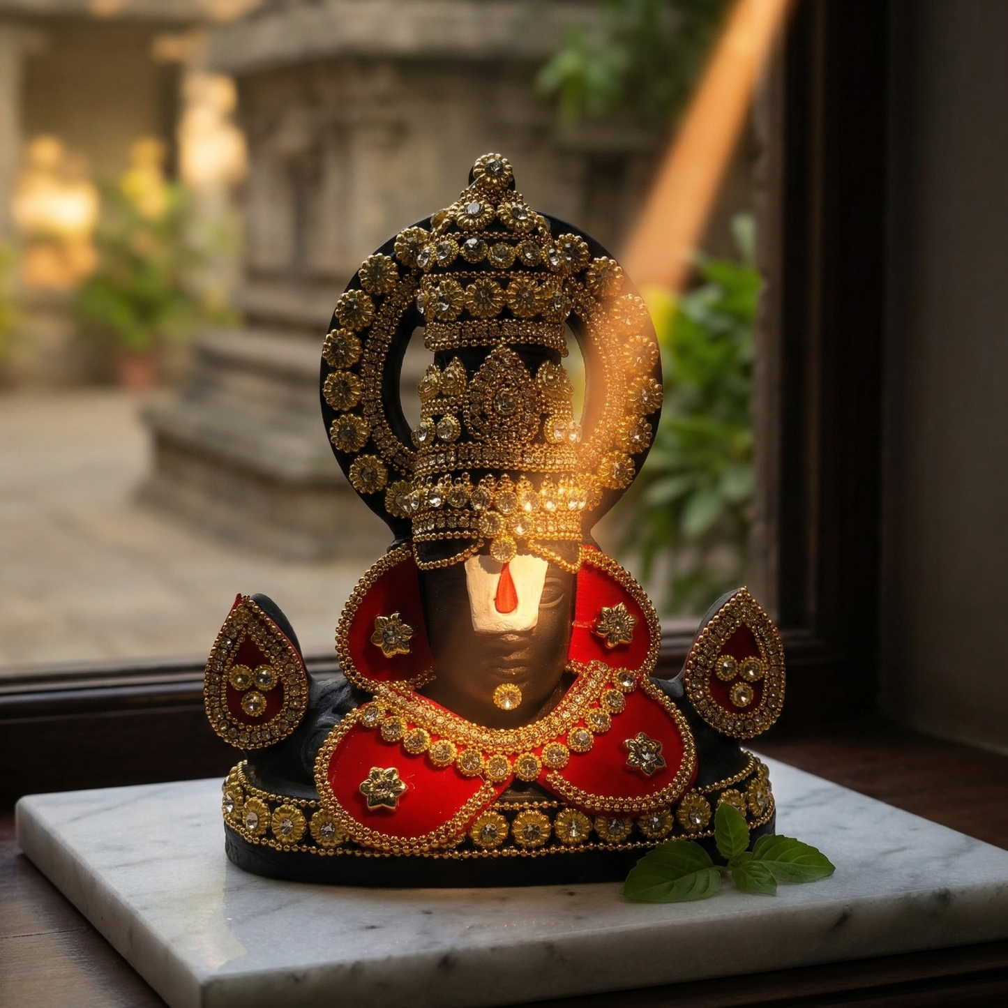 Black Tirupati Balaji divine face adorned with red and gold-tone stone embellishments on a mable sunlight hitting the tilak of lord Balaji.
