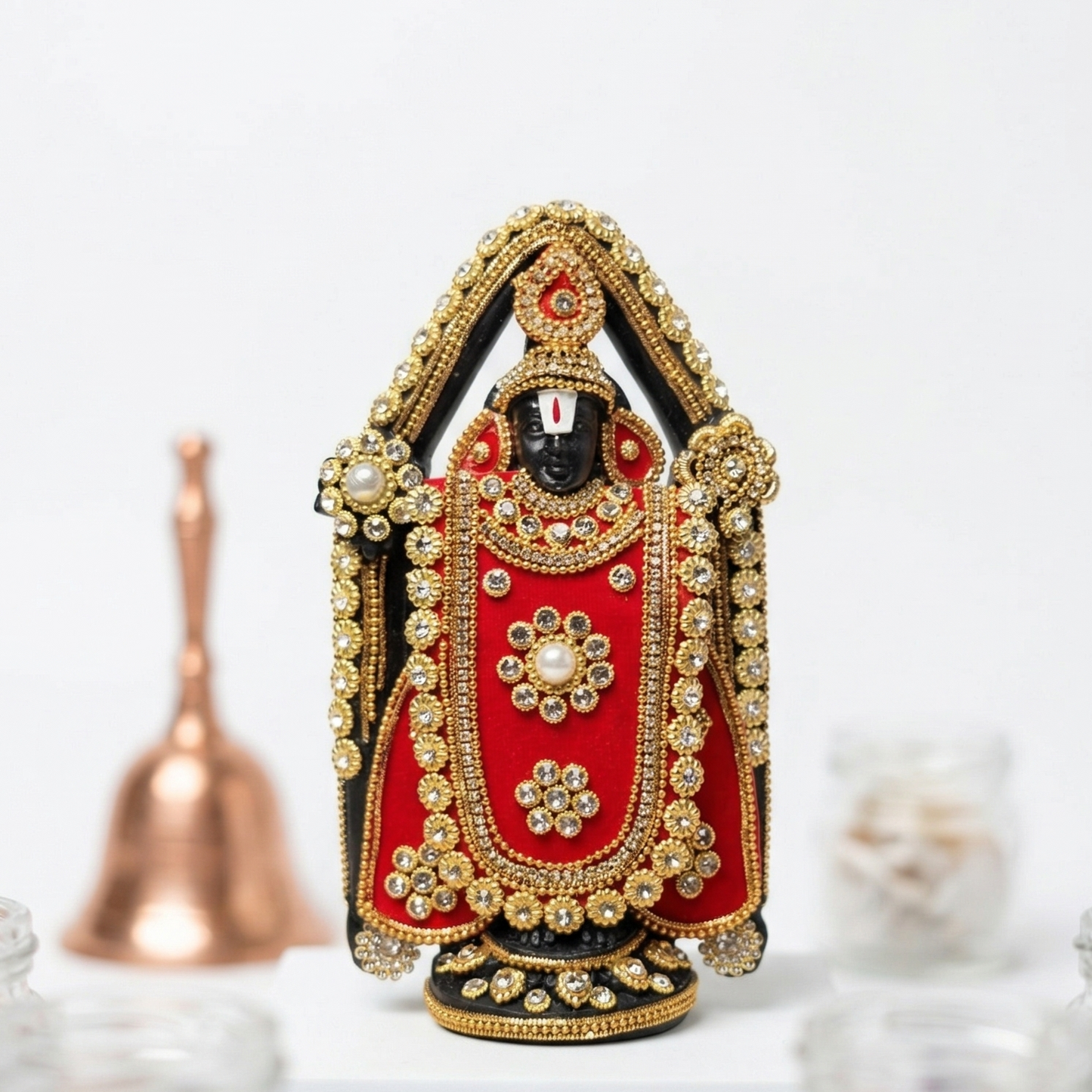 Handcrafted black Lord Venkateswara (Tirupati Balaji) murti richly adorned with red fabric, gold-tone detailing, and sparkling stones against a white background