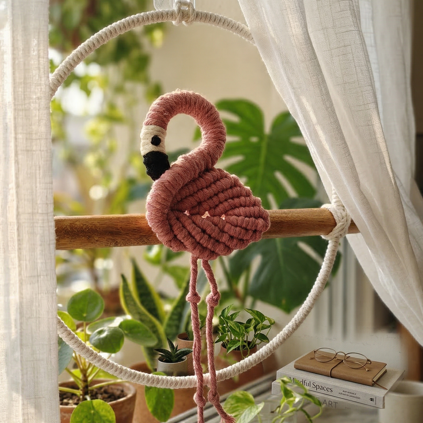 Handcrafted macrame pink flamingo wall hanging closeup sitting on wooden perches.