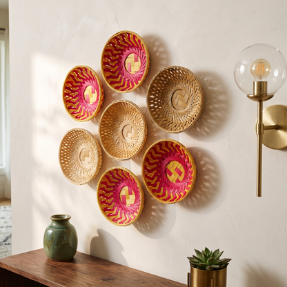 Six circular woven bamboo wall baskets featuring natural and bright pink geometric patterns, hung as a decorative cluster above a wooden console table next to a glass globe sconce.