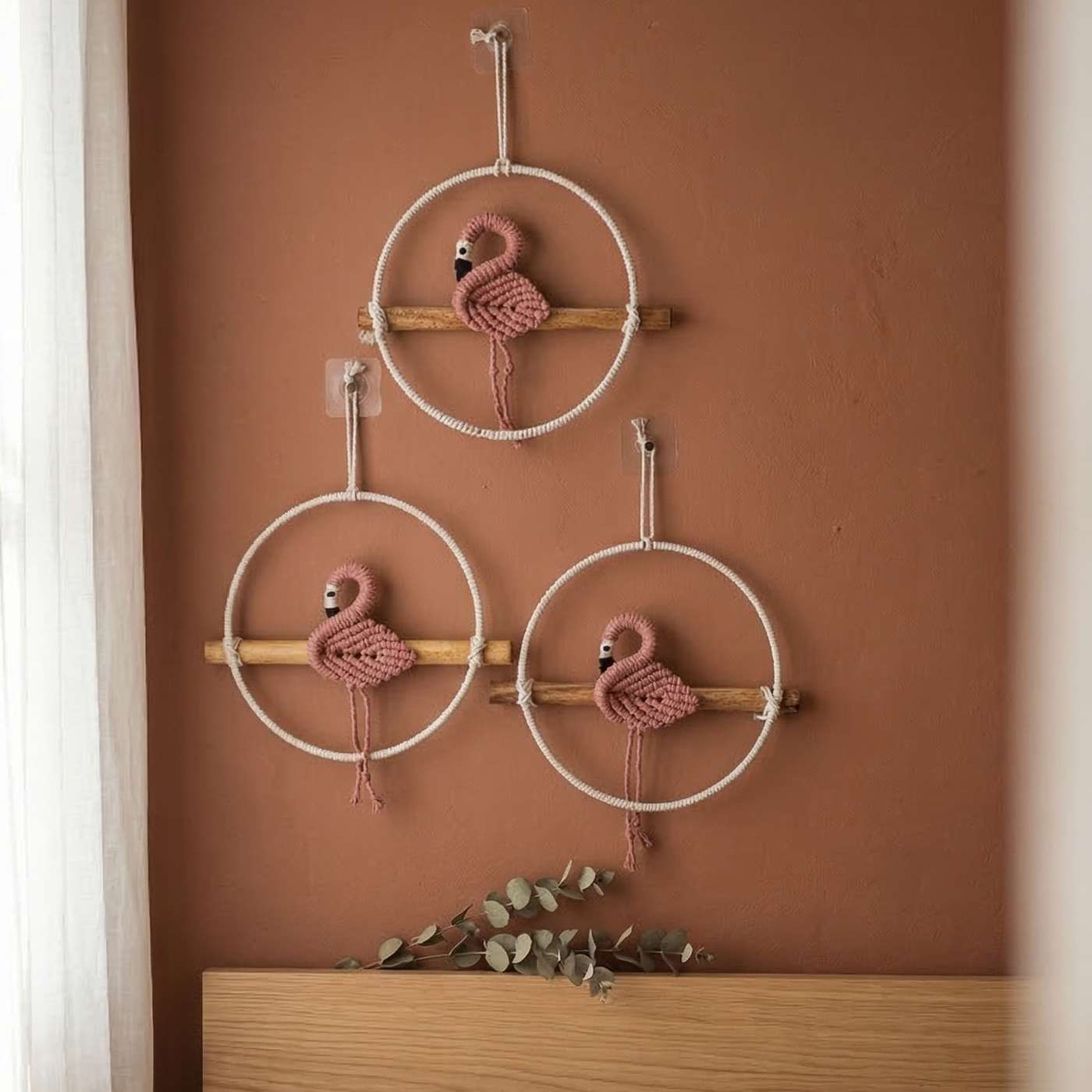 Set of 3 handcrafted macrame pink flamingo wall hangings sitting on wooden perches placed in a bedroom
