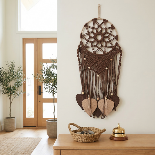 Decorative wall hanging with leaves and a dreamcatcher design in a room with a wooden table and plants.