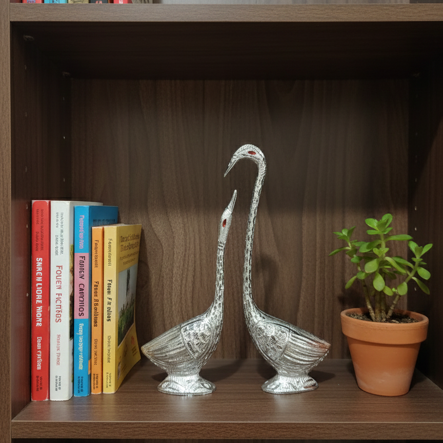 Decorative white metal swan statue placed on a wooden bookshelf next to books and a small plant, perfect for office or home library decor.