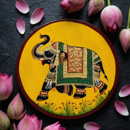 Close-up flat lay of Pichwai Elephant Art Plate surrounded by pink lotus flowers.