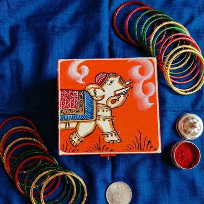Orange hand-painted wooden storage box with traditional elephant art, used for jewelry and trinkets.
