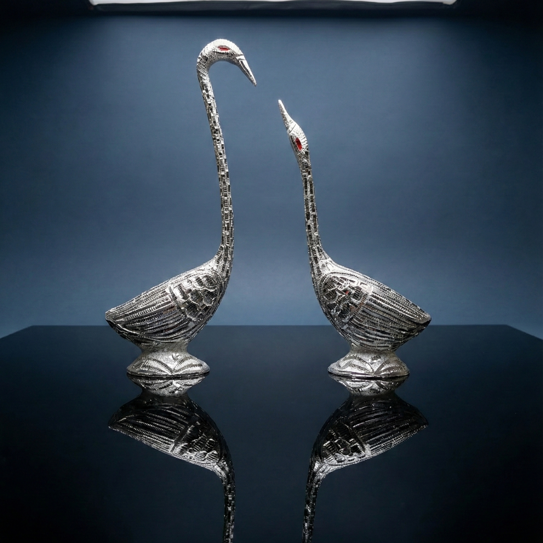 Studio shot of a silver swan couple figurine set on a reflective black surface, highlighting the premium finish for luxury gifting.