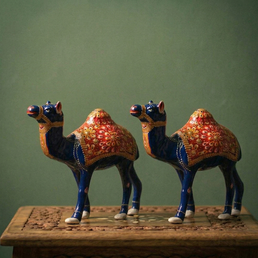Decorative Meenakari Metal camel figurines on a wooden shelf with a green wall in the background