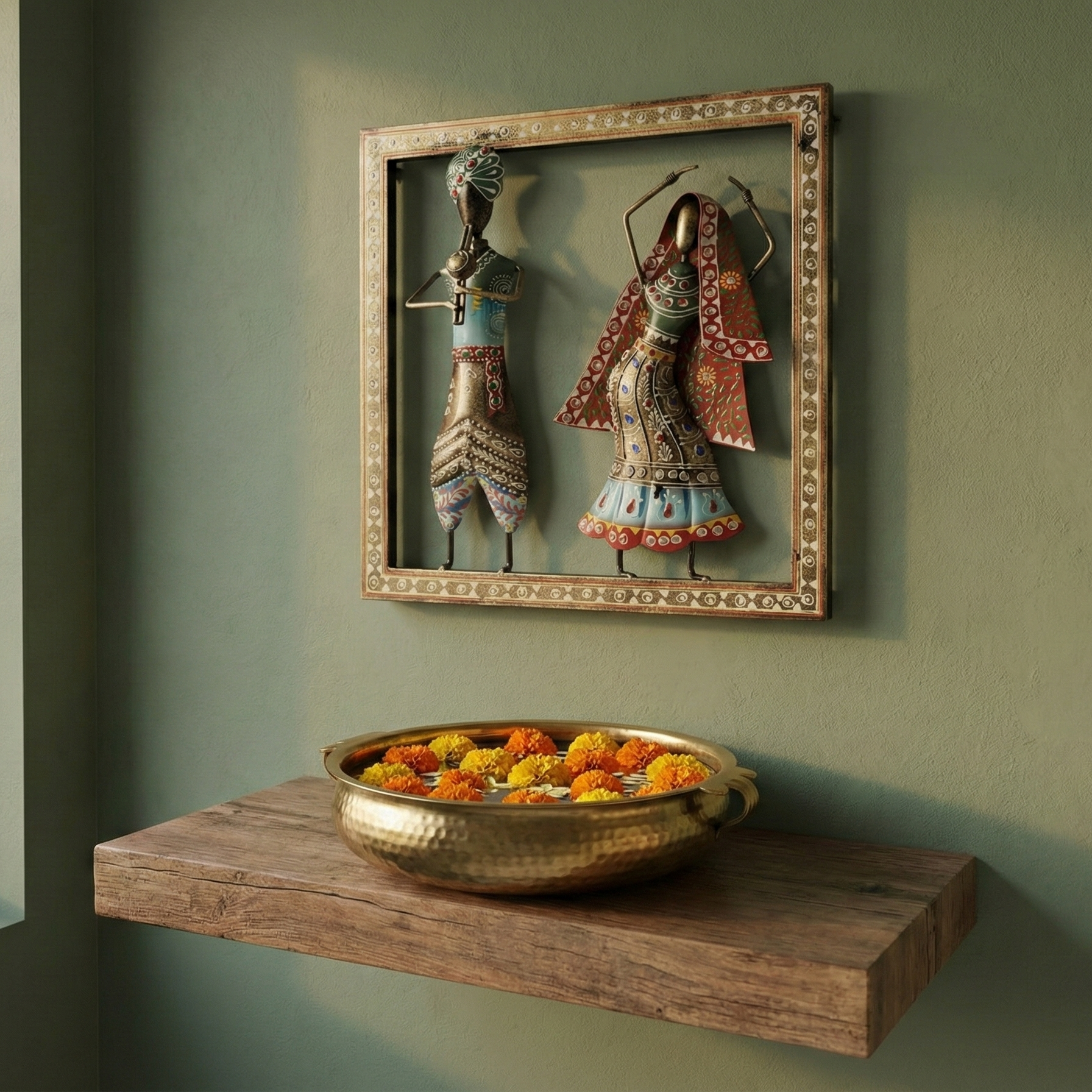 Wrought iron Kalbelia dancer and musician wall hanging displayed above a wooden shelf with flowers. Perfect ethnic wall decor for entryways or puja rooms.