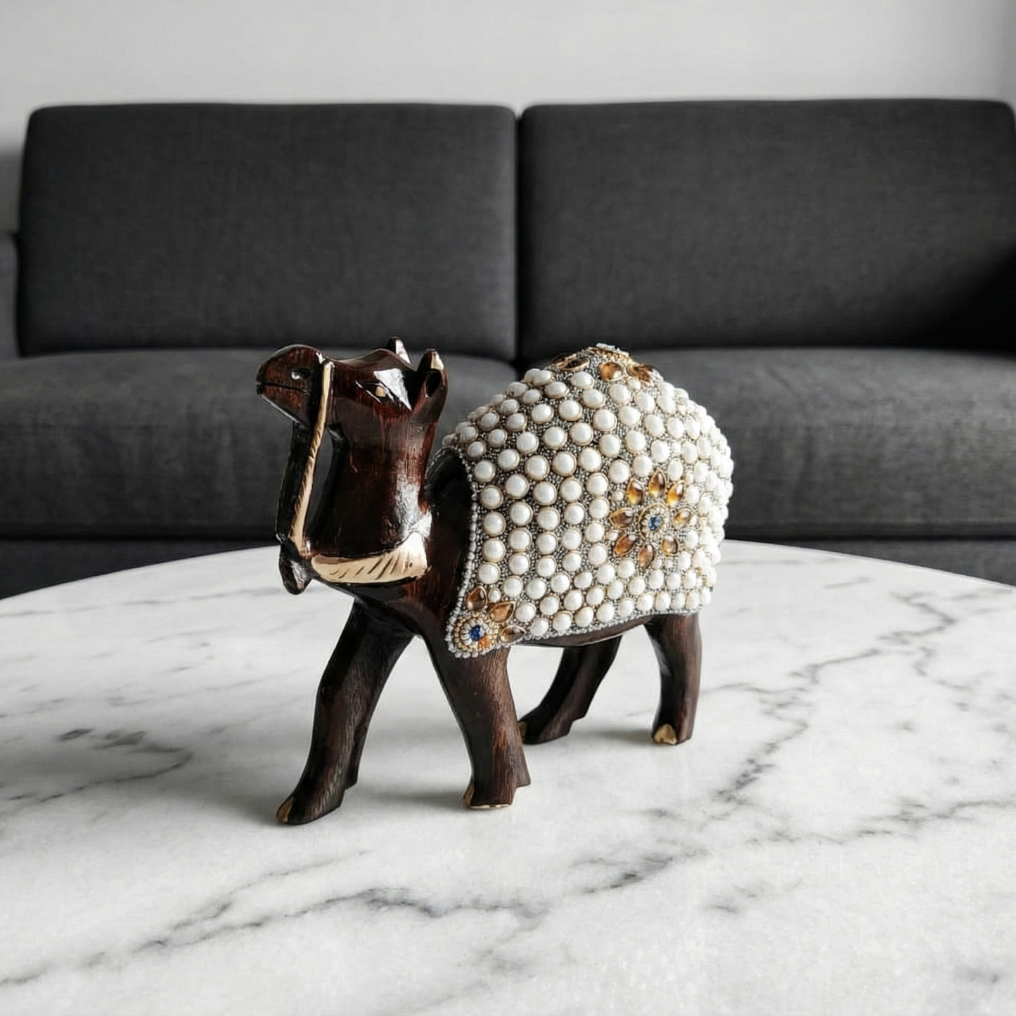 Hand-carved wooden camel figurine with pearl work placed on the centre table in the living room